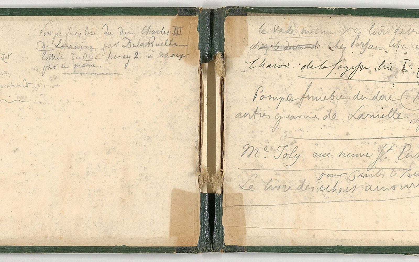 Open notebook with green covers showing handwritten French notes in pencil on both pages