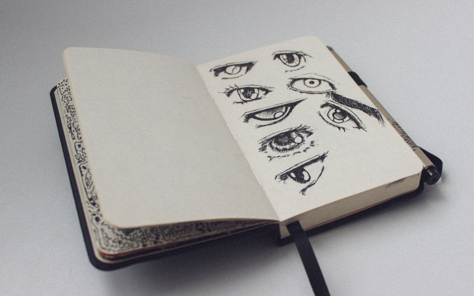 An open sketchbook page filled with pen drawings of eyes in various styles and angles