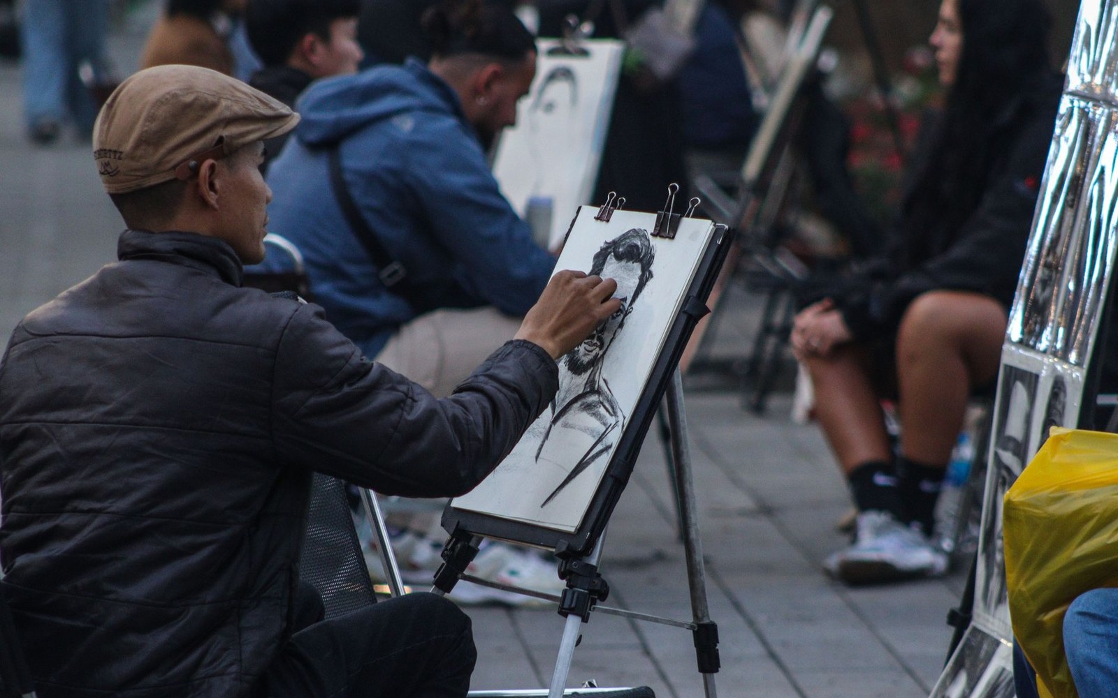 Street artist sketches a portrait in charcoal on an easel outdoors
