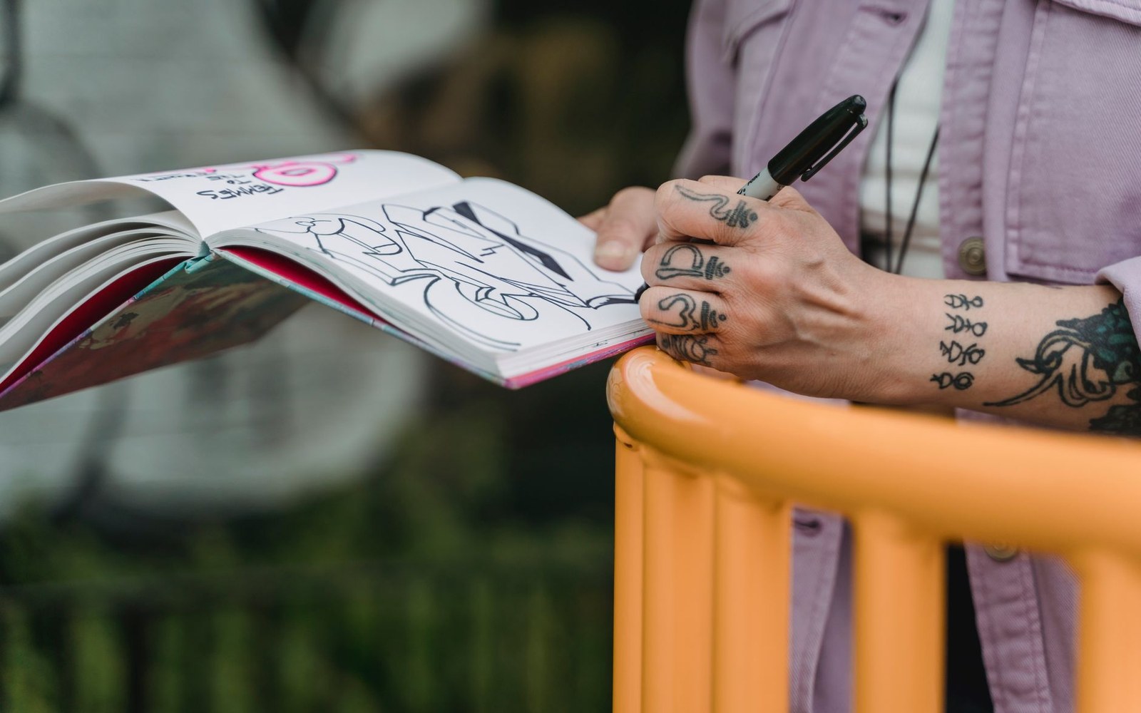 A pocket sketchbook open on a knee with a line half-drawn